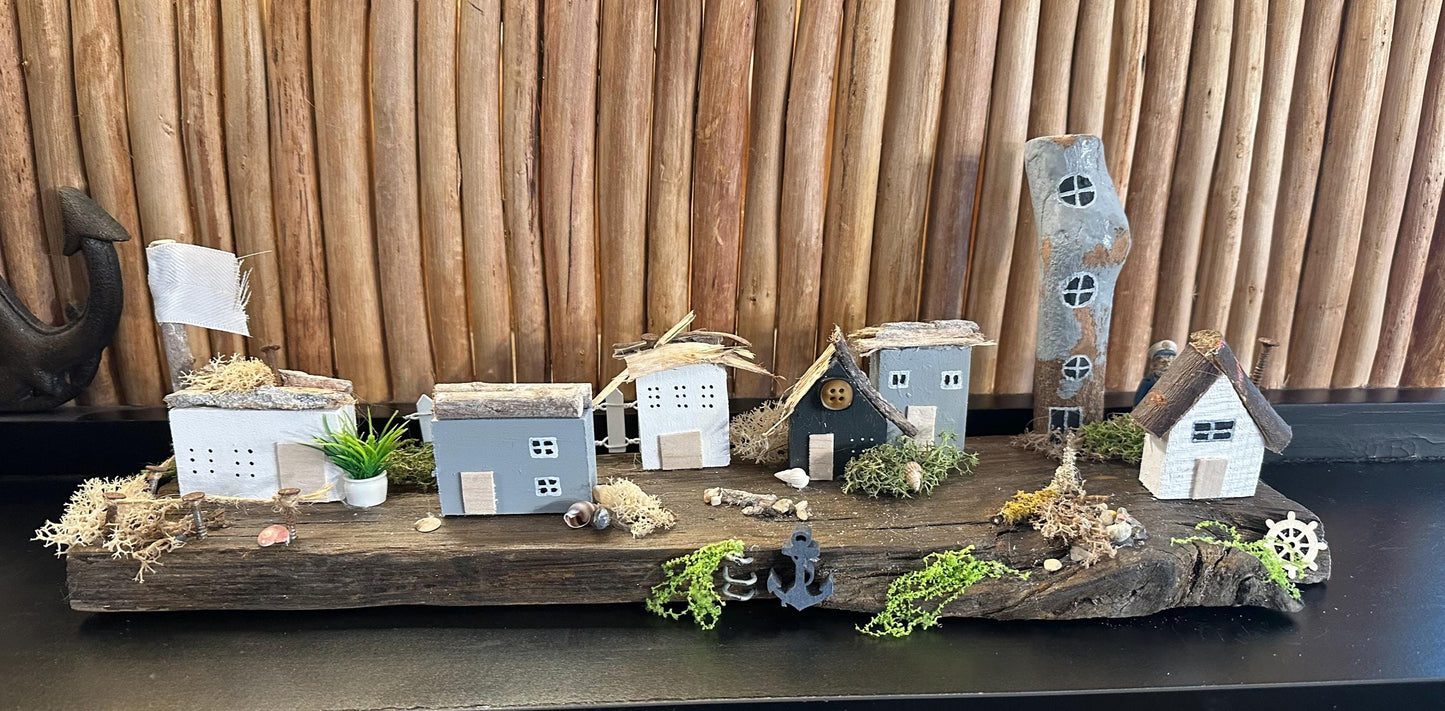 Handcrafted driftwood coastal village displayed on a rustic wooden surface,
featuring miniature houses, a lighthouse, a sailboat, anchor, and steering
wheel. Natural elements like moss and stones enhance the seaside theme.
The arrangement evokes a peaceful oceanic scene, perfect for beach house
or coastal home decor. A “Rare find” label and price tag suggest its
uniqueness and gift appeal.